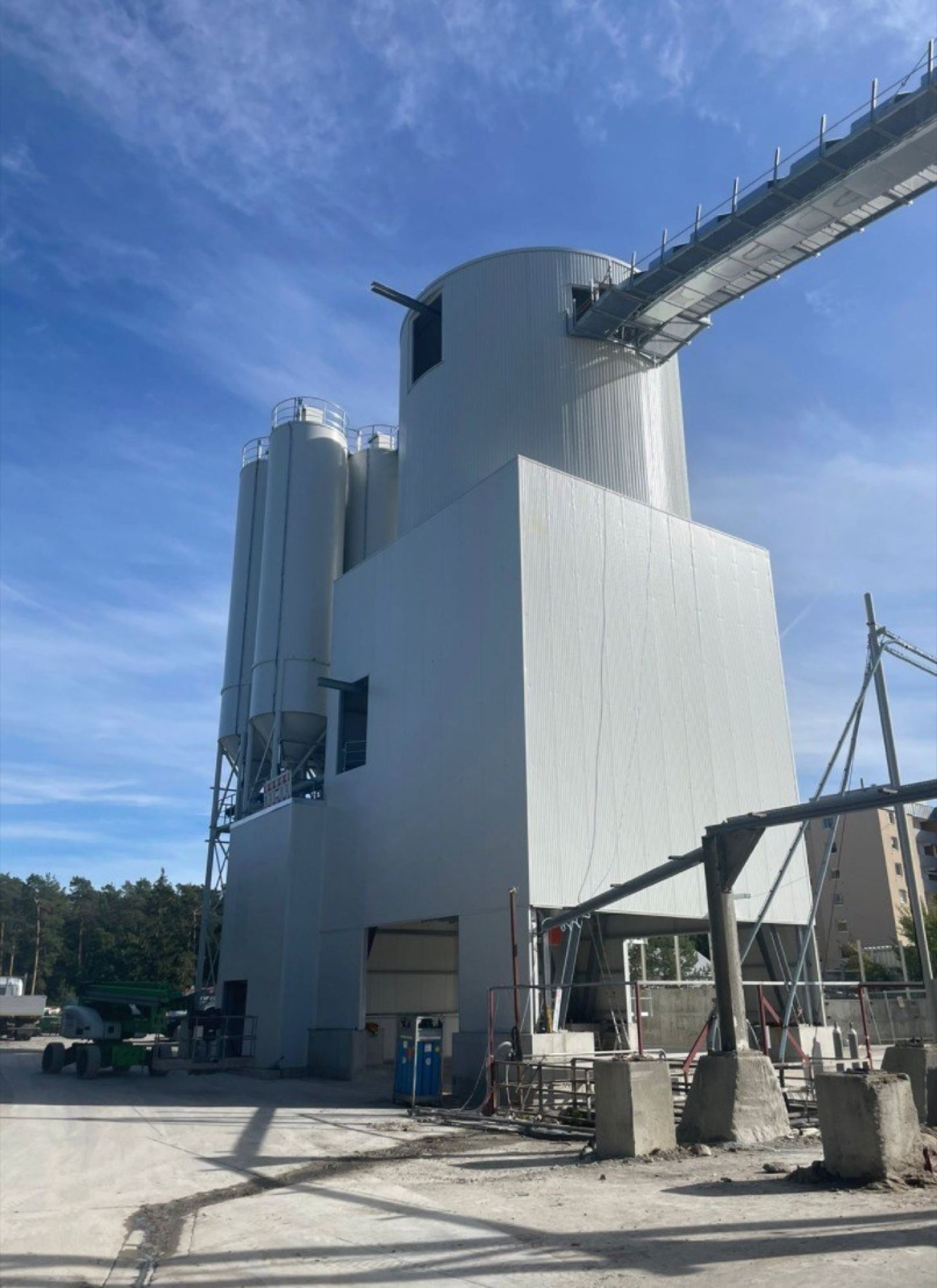 Upward view of a NISBAU PRO Tower storage silo, conveyor bridges and access structure against a blue sky